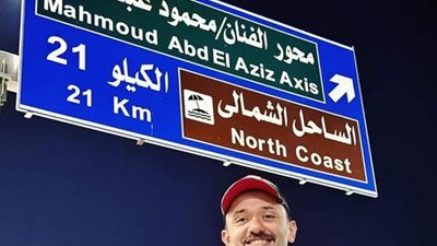  كريم محمود عبدالعزيز يلتقط صورة أسفل لافتة أحد المحاور باسم والده