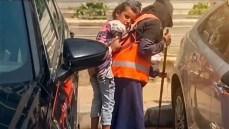 أم فارس تحمل نجلها على ظهرها أثناء العمل 